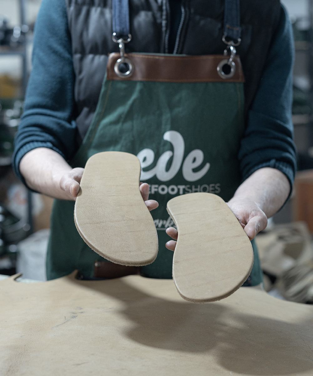 Craftsman holding hand-cut buffalo leather soles at THE SHOE ATELIER
